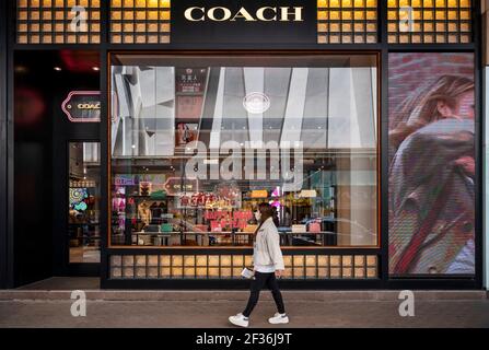 Ein Fußgänger geht vorbei an der amerikanischen multinationalen Mode und Luxus-Accessoires-Kette Marke, Coach Store und Logo in Hongkong. Stockfoto