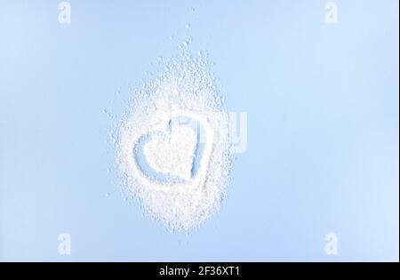 Herz aus weißem Salz auf blauem Hintergrund. Leerzeichen für Text. Stockfoto
