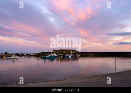 Lyme Regis, Dorset, Großbritannien. 15th. März 2021. UK Wetter: Der Abendhimmel über dem Cobb Hafen bei Lyme Regis leuchtet kurz nach Sonnenuntergang mit rosa und lila Farbtönen. Kredit: Celia McMahon/Alamy Live Nachrichten. Stockfoto