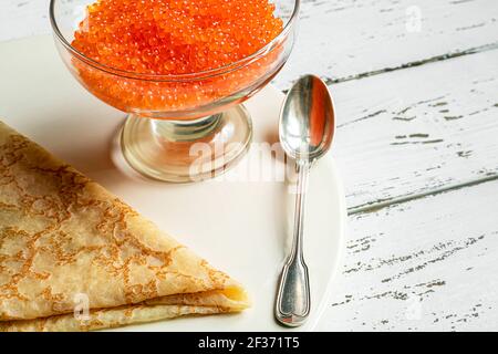 Traditionelle russische Küche: Pfannkuchen aus Weizenmehl und rotem Kaviar auf einem weißen Tisch Stockfoto