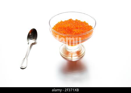 Köstlicher roter Kaviar in einem transparenten Glas und einem Silber Löffel isoliert auf weißem Hintergrund Stockfoto