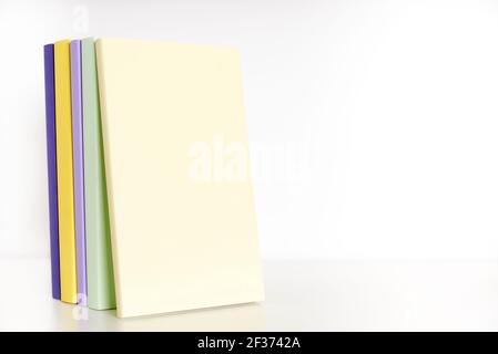 Farbige Bücher mit leerem Rücken auf einem weißen Regal mit weißem Hintergrund. Konzepte des Lesens und der Bildung. Helles Bild mit Kopierbereich. Stockfoto