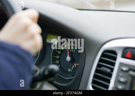 Selektives Fokusbild des Fahrzeuginnenraums. Fokus auf analogem Tachometer - Überdrehung Konzept. Fahrer Hände auf Lenkrad. Hochwertige Fotos Stockfoto