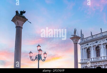 Die Säulen der Piazzetta - Saint Mark und Saint Theodore und ein Laternenpfosten auf dem Markusplatz in den frühen Morgenstunden in Venedig in Venetien, Italien Stockfoto