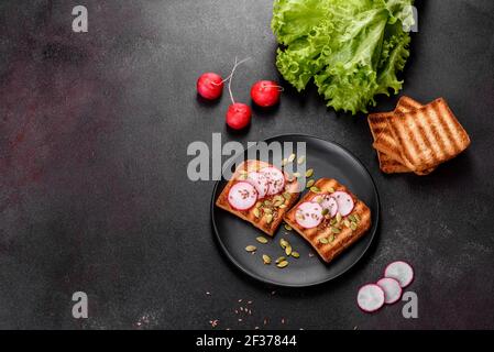 Köstliches knuspriges Sandwich mit Toast, Rettich, Kürbiskernen und Leinsamen. Vegetarische Küche Stockfoto