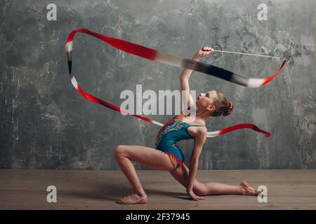 Junge Mädchen professionelle Turnerin Frau tanzen rhythmische Gymnastik mit Band im Studio. Stockfoto