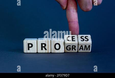 Prozess- und Programmsymbol. Geschäftsmann dreht Holzwürfel und ändert das Wort "Programm" in "Prozess". Schöner grauer Hintergrund. Geschäft, Prozess A Stockfoto