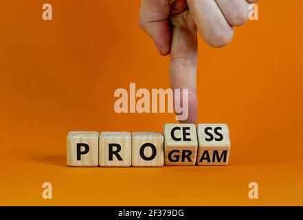 Prozess- und Programmsymbol. Geschäftsmann dreht Holzwürfel und ändert das Wort "Programm" in "Prozess". Schöner orangefarbener Hintergrund. Geschäft, Prozess Stockfoto