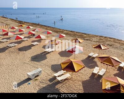 Strand mit Sonnenschirmen und schmutziges Meer, das viele Algen bringt Zum Ufer Stockfoto