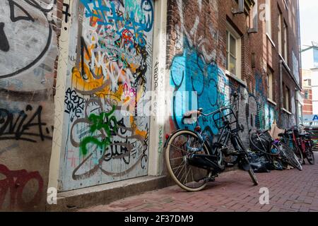 Reihe von Fahrrädern in leeren Gasse mit Graffiti auf geparkt Die Wände Stockfoto