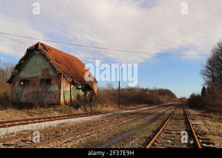 Ein völlig beschädigtes Gebäude des alten österreichisch-ungarischen Bahnhofs Und die umliegende Vegetation irgendwo in Bosnien und Herzegowina Stockfoto