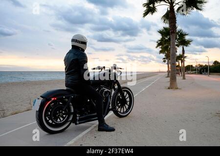 Rückansicht eines Motorrades steht neben einem Strand Mit seinem Besitzer allein Stockfoto