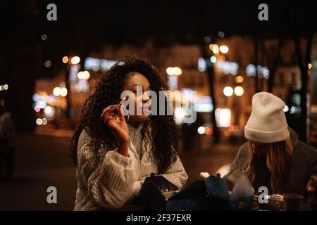 Junge Frauen essen Street Food stehen am Tisch in der Stadt Nachts Stockfoto