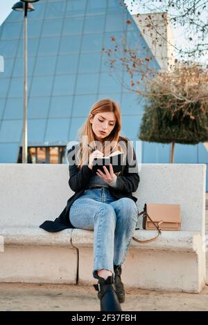 Frau schreibt in ihrem Notizbuch mit einem Handelsgebäude bei Ihr Rücken Stockfoto