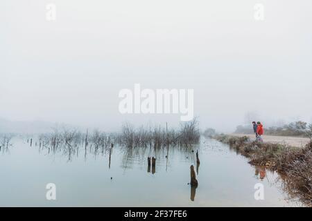Zwei Brüder stehen am See im Winter bei nebliger Bewölkung Himmel Stockfoto
