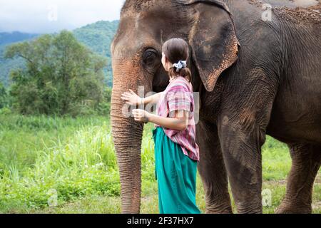 Nördlich von Chiang Mai, Thailand. Ein Mädchen streichelt einen Elefanten in einem Heiligtum für alte Elefanten. Stockfoto