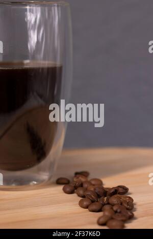 americano in einem Doppelboden Glas in der Nähe Kaffeebohnen auf Holzplatte. Kaffeepause. Stockfoto