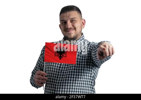 Weißer Kerl hält eine Flagge Albaniens und zeigt vor ihm isoliert auf weißem Hintergrund nach vorne. Stockfoto