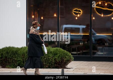 BELGRAD, SERBIEN - 29. NOVEMBER 2020: Selektive Unschärfe auf eine alte ältere Frau mit einer Atemschutzmaskenmaskin, die während des coro vor einem Café mit läuft Stockfoto