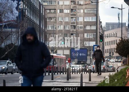 BELGRAD, SERBIEN - 14. FEBRUAR 2021: Selektive Unschärfe auf jungen Mann mit einer Atemmaske beim Spaziergang in den Straßen von Belgrad, während der coron Stockfoto