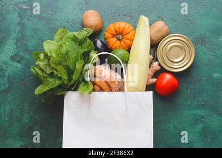 Papiertüte mit verschiedenen Produkten auf farbigem Hintergrund Stockfoto