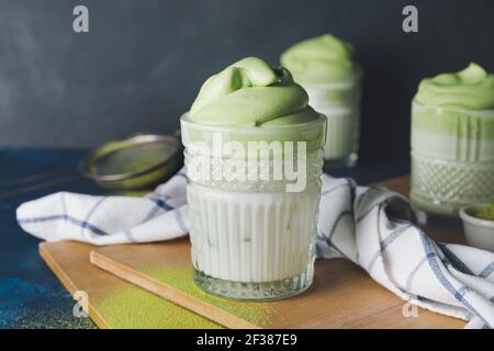 Gläser schmackhafter dalgona Matcha Latte auf dunklem Hintergrund, Nahaufnahme Stockfoto