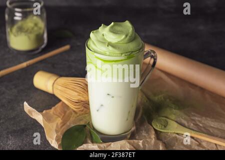Komposition mit schmackhaftem Dalgona Matcha Latte auf dunklem Hintergrund Stockfoto