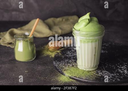 Komposition mit schmackhaftem Dalgona Matcha Latte auf dunklem Hintergrund Stockfoto
