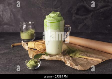 Komposition mit schmackhaftem Dalgona Matcha Latte auf dunklem Hintergrund Stockfoto