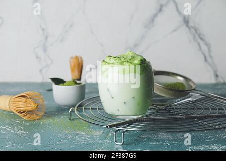 Zusammensetzung mit leckeren dalgona Matcha Latte auf dem Tisch gegen Licht Hintergrund Stockfoto