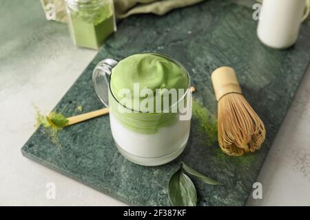 Zusammensetzung mit leckeren dalgona Matcha Latte auf dem Tisch Stockfoto