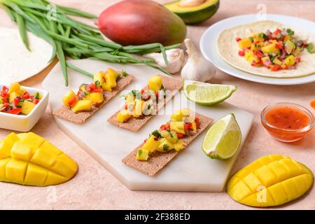 Komposition mit frischer Mango-Salsa und Knäckebrot auf farbigem Hintergrund Stockfoto