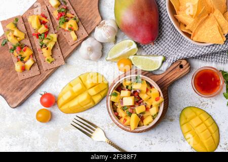 Komposition mit frischer Mango-Salsa, Knäckebrot und Nachos auf hellem Hintergrund Stockfoto