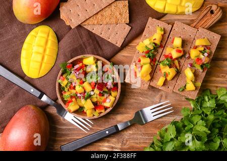 Komposition mit frischer Mango-Salsa und Knäckebrot auf Holzgrund Stockfoto