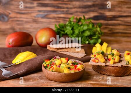 Schale mit frischer Mangosalsa auf Holzhintergrund Stockfoto