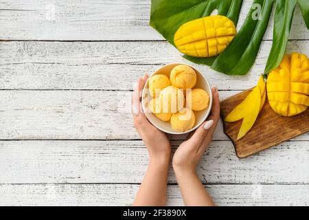 Frau mit Mango-Eis auf hellem Holzhintergrund Stockfoto