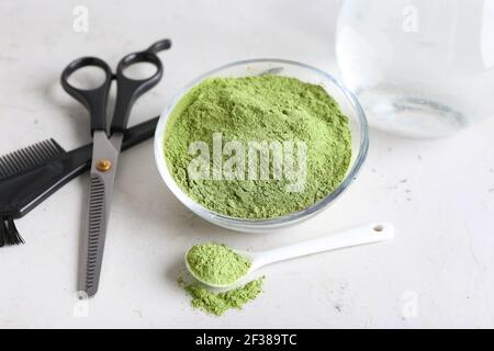 Schüssel mit Henna, Glas Wasser und Friseurbedarf auf hellem Hintergrund Stockfoto