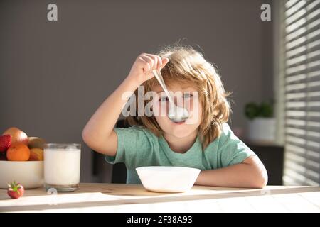 Abendessen für Kinder. Portrait von Spaß Kind mit gesunden leckeren Snack. Kleines Kind verrückt posiert durch Küchentisch. Stockfoto