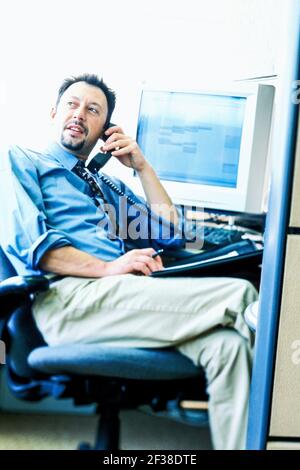 Geschäftsmann der 1990er Jahre in einer Bürozelle, die am Telefon spricht. Stockfoto