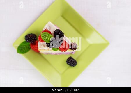 Ein Stück Kuchen mit frischen Beeren und Minze auf der Oberseite. Stockfoto