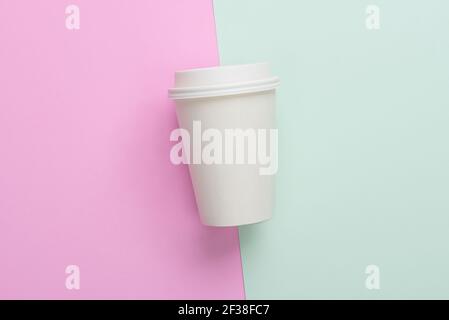 Zum Mitnehmen (zum Mitnehmen) Kaffeetasse auf hellblauem und rosa Hintergrund Stockfoto