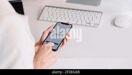 CHIANG MAI, THAILAND MAR 13, 2019 : EINE Frau hält ein iPhone 12 mit Social-Network-Service LinkedIn auf dem Bildschirm. IPhone 12 wurde erstellt und Stockfoto