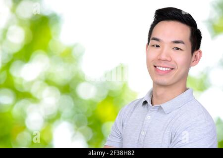 Lächelnder junger asiatischer Mann auf Bokeh grün abstrakten Hintergrund Stockfoto