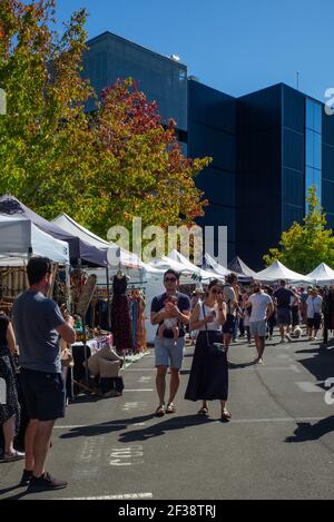 Ein Paar mit einem Baby auf dem Smal Farm Sunday Market, Takapuna, Auckland, ein Ort, um sich zu treffen, Kaffee zu trinken und Kunsthandwerk zu sehen und zu kaufen. Stockfoto