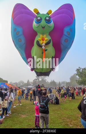 Ein Heißluftballon in Form eines niedlichen Schmetterlings, der über einer Menschenmenge schwebt. Balloons Over Waikato Festival, Hamilton, Neuseeland Stockfoto