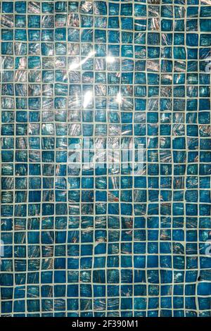Ein Pool mit blauen Keramikfliesen und Wasserwelligkeit Effekt. Rückbefall von blauem Wasser im Schwimmbad mit Ripple. Nahaufnahme einer türkisfarbenen Mosaikfliesen Stockfoto
