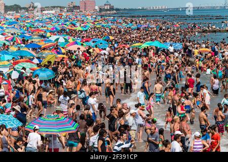 Endlose Schwärme von Menschen und ihre Sonnenschirme packen am 4th. Juli 2017 das Ufer auf Coney Island. Stockfoto