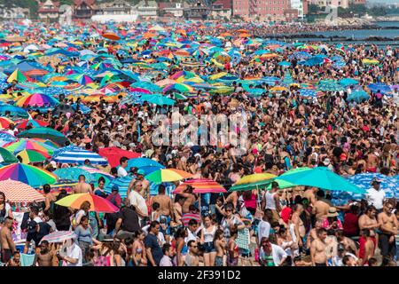 Endlose Schwärme von Menschen und ihre Sonnenschirme packen am 4th. Juli 2017 das Ufer auf Coney Island. Stockfoto