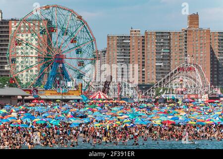 Endlose Schwärme von Menschen und ihre Sonnenschirme packen am 4th. Juli 2017 das Ufer auf Coney Island. Stockfoto