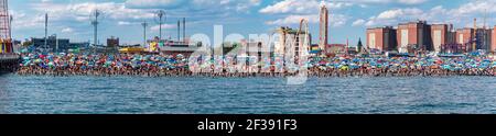 Endlose Schwärme von Menschen und ihre Sonnenschirme packen am 4th. Juli 2017 das Ufer auf Coney Island. Stockfoto